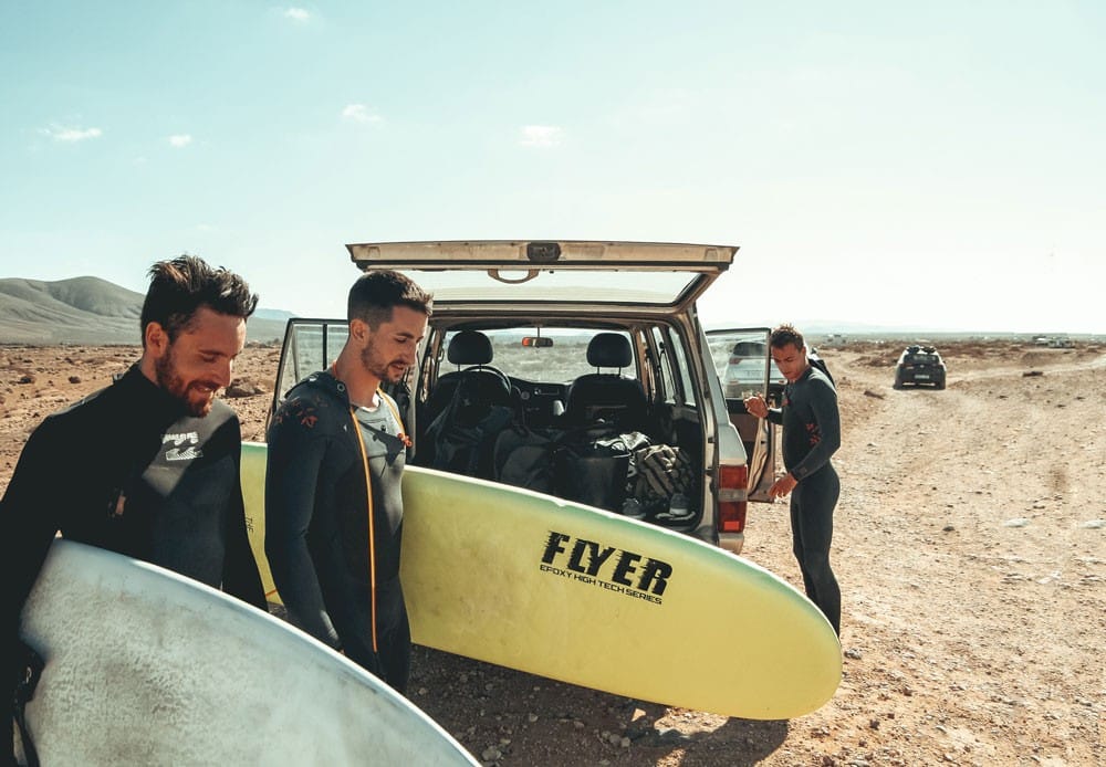 tres chicos con una tabla de surf sonriendo